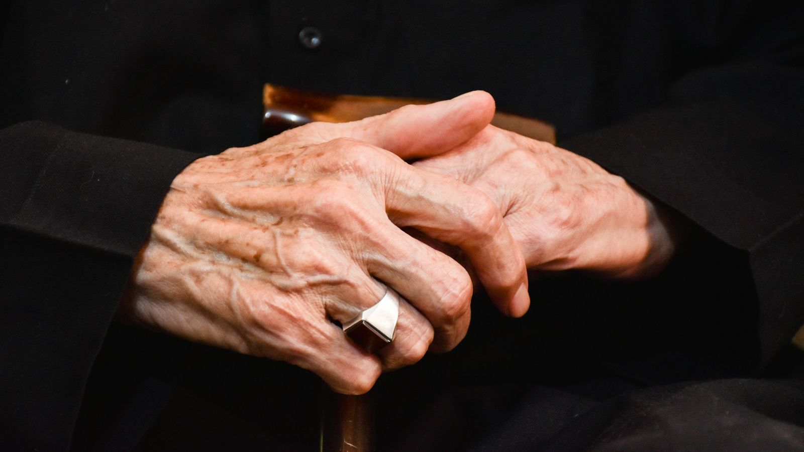 Elderly hands being held.
