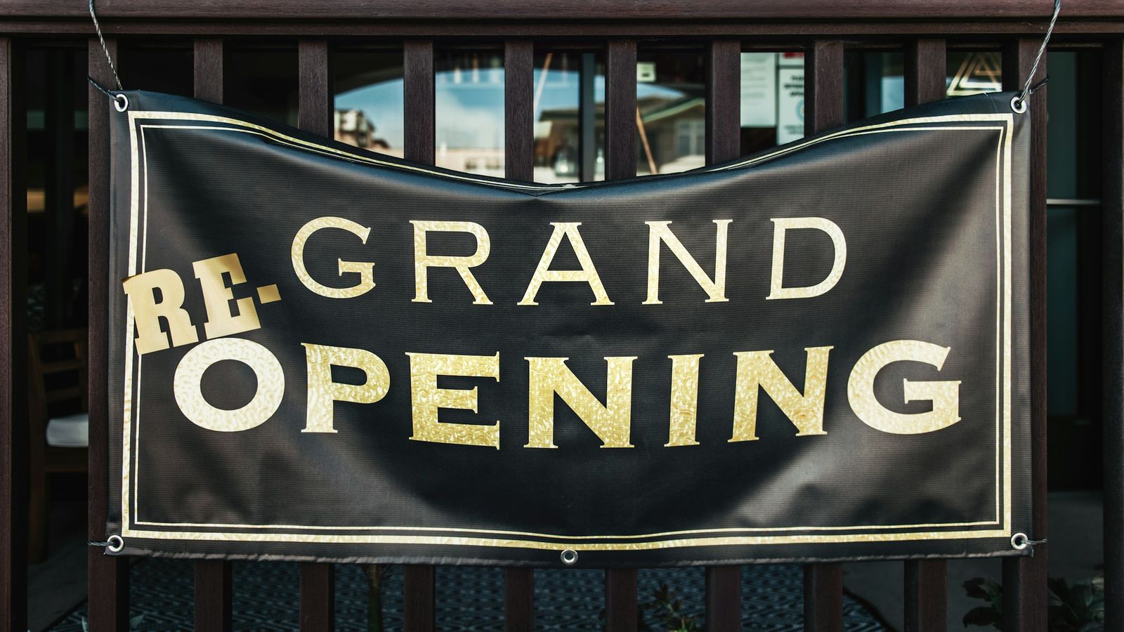 A re-grand opening sign hanging on a gate.