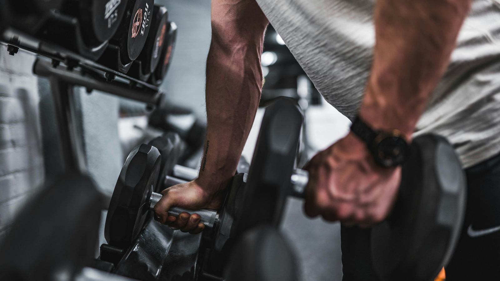 A man lifting dumbbells off of a rack.
